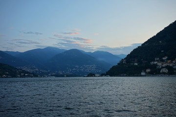 The sun rises over the Alps and Lake Como. View from the promenade of Como.