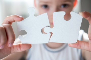 boy is holding a large white puzzle. the child learns to collect puzzles. development, training concept