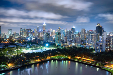 Fototapeta na wymiar Cityscape, many modern building of midtown at night beautiful lighting, lake in park is foreground