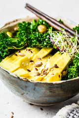 Kale salad with avocado and sprouts in a bowl. Healthy vegan food concept.