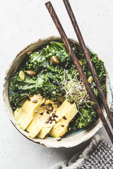 Kale salad with avocado and sprouts in a bowl. Healthy vegan food concept.
