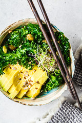 Kale salad with avocado and sprouts in a bowl. Healthy vegan food concept.