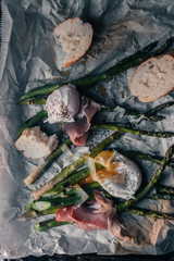 Poached eggs with asparagus and prosciutto on a parchment paper and plate