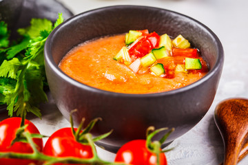 Traditional cold gazpacho tomato soup in black bowl on a gray background.