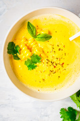 Vegan corn cream soup in white bowl on a gray background, top view.