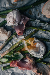 Poached eggs with asparagus and prosciutto on a parchment paper and plate