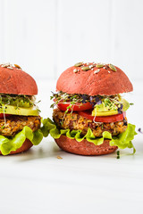 Pink vegan burgers with beans cutlet, avocado and sprouts on white background.