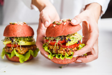 Cooking pink vegan burgers with beans cutlet, avocado and sprouts on white background.