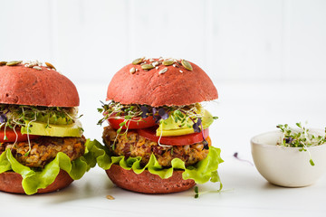 Pink vegan burgers with beans cutlet, avocado and sprouts on white background.
