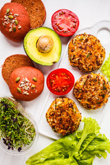 Ingredients for vegan burgers on a white background. Beans burgers, pink beetroot buns, sprouts, avocado and vegetables.