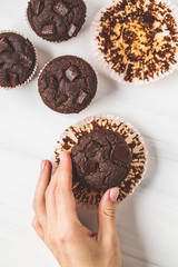 Chocolate vegan muffin in hand  on white background.