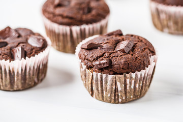 Chocolate vegan muffin in a paper cup on white background.
