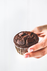 Chocolate vegan muffin in a paper cup on white background.