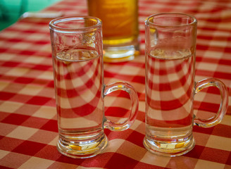 Vodka alcohol shot glass kept in a pattern around a beer glass during the gathering of friends outdoor