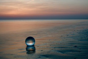ruhige Abendstimmung mit sonnenuntergang am strand mit  glaskugel im Sand