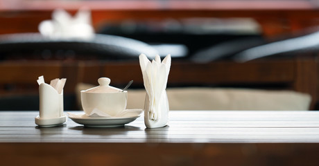Table in a cafe or restaurant. White napkins, spices and sugar on a wooden table, panoramic view