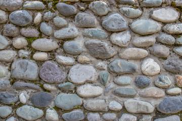 Wall of round stone and concrete on a summer day