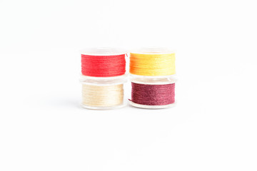 Four spools of beige, yellow, red and burgundy threat prepared for the sewing machine, isolated on...