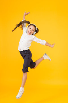 The best dancer. Adorable small dancer moving to music playing in headphones. Little dancer performing ballet leap on yellow background. Cute girl dancer dancing back to school dance