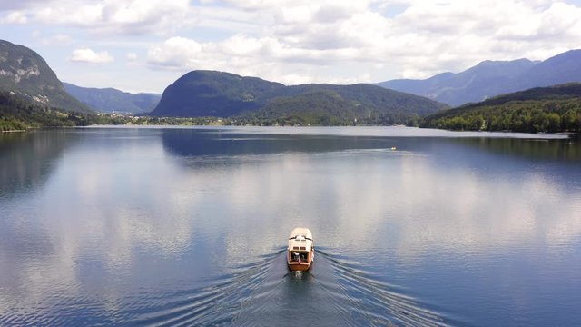 Aerial follow footage of a small Tourist Boat sailing slowly at Lake Bohinj, Slovenia.