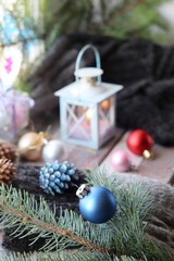 Christmas decor, spruce branch, balls, woolen plaid, lantern with a burning candle on a window background, seasonal winter celebrations