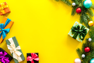 Frame from gifts in boxes and spruce for new year eve on yellow background top veiw mockup