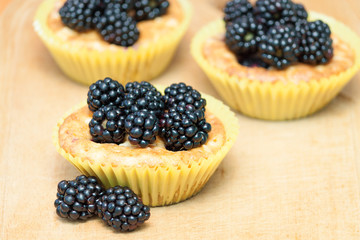 Homemade cupcakes or muffins with berries blackberries on wooden table. Fresh berries and sweet pastries.