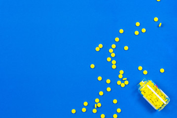 Yellow pills and bottle on a blue background. Copy space for text.