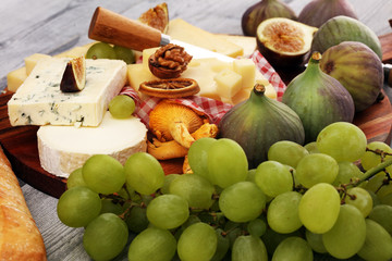 Cheese platter with different cheese and grapes and figs and nuts.