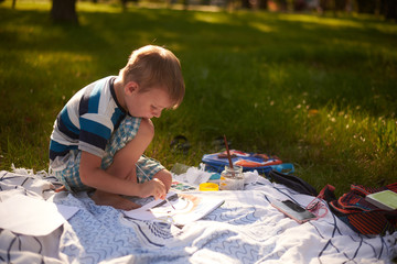 a boy of five to six years old draws in nature