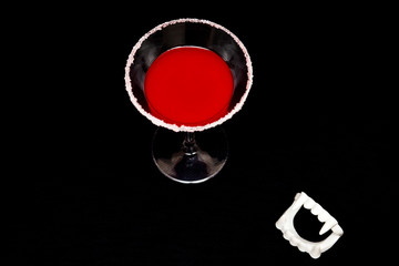 Bloody vampire drink with fangs for halloween on black background with space for copy text. 