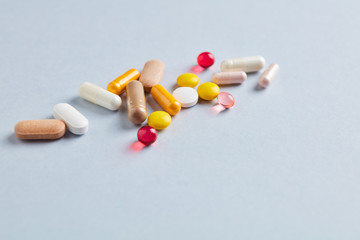 Multicolor vitamins and supplements on bright paper background. Concept for a healthy dietary supplementation. Copy space. 