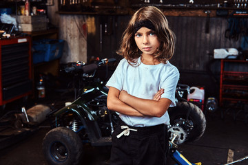 Pensive little girl is posing for photographer crossed her hands at auto service.