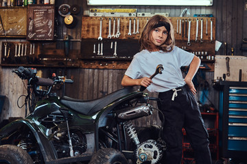 Naklejka na ściany i meble Serious beautiful girl want to be an auto technician when she grows up, she is trying to fix broken ATV.