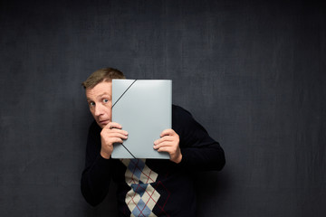Portrait of afraid man curiously looking out from folder