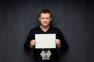 Portrait of angry man holding white blank paper sheet