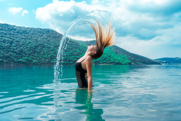 Beautiful girl splashing in the water. Colorful turquoise landscape. Rest, relax. Summertime. Vacation. Journey. In nature. Tropical. Enjoy life. Lifestyle. A young woman swimming in the lake. Island