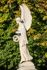 Statue of ancient beautiful winged angel in downtown park of Potsdam in beginning of Autumn at...