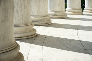 White marble neoclassical columns casting shadows in a rotunda