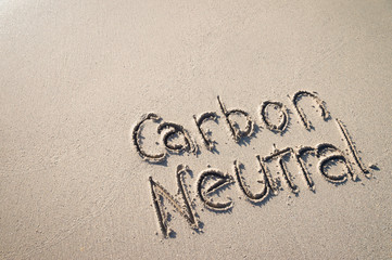 Carbon Neutral message handwritten on smooth sand beach 