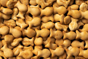 Background from a large number of small cookies in the shape of fish golden brown, close-up