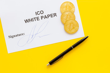 White paper ICO, coins, pen on yellow background top view