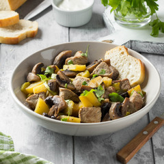 Roast meat (pork, beef) with potatoes, zucchini and mushrooms. Autumn fried stew with sour cream and parsley, traditional food, hearty tasty lunch