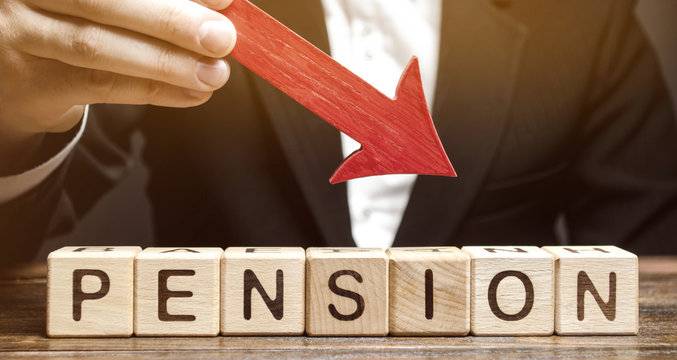 A man holds an arrow down over wooden blocks with the word Pension. Fall / reduction pension payments. Retirement. Financing retirees. Reduction of the pension fund. The low size of pensions.
