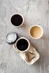 Caution: contents hot. Paper cups with black coffee and cappuccino to take away on gray background top view