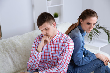 Upset couple sitting at the sofa. Couple problem concept