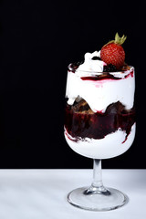 dessert in bowl with fruits on black background.