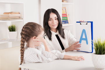 Woman with kid girl training speech together sitting in the white room