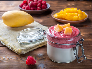 Panna cotta with mango and raspberry sauce on wooden background. Selective focus