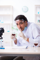 Male chemist examining wine samples at lab